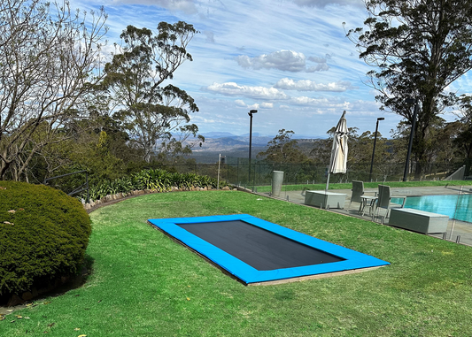 Inground trampoline in backyard with pool and view of valley