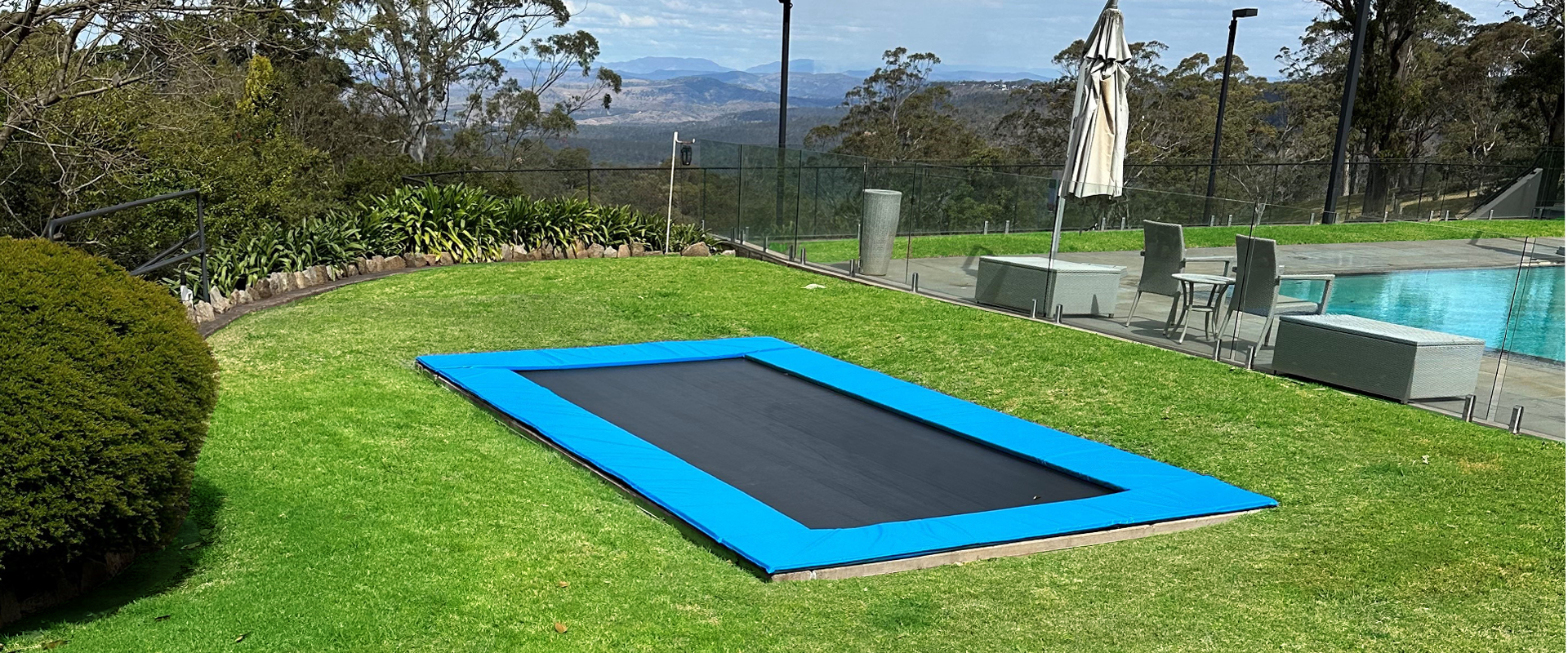 Rectangular inground trampoline in backyard with pool and view of valley